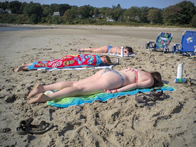 Lauren, Kiersten, and Grace lie face-down in the sun