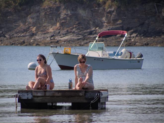 Lauren and Kiersten relaxing on the floating dock with a small boat moored in
the background